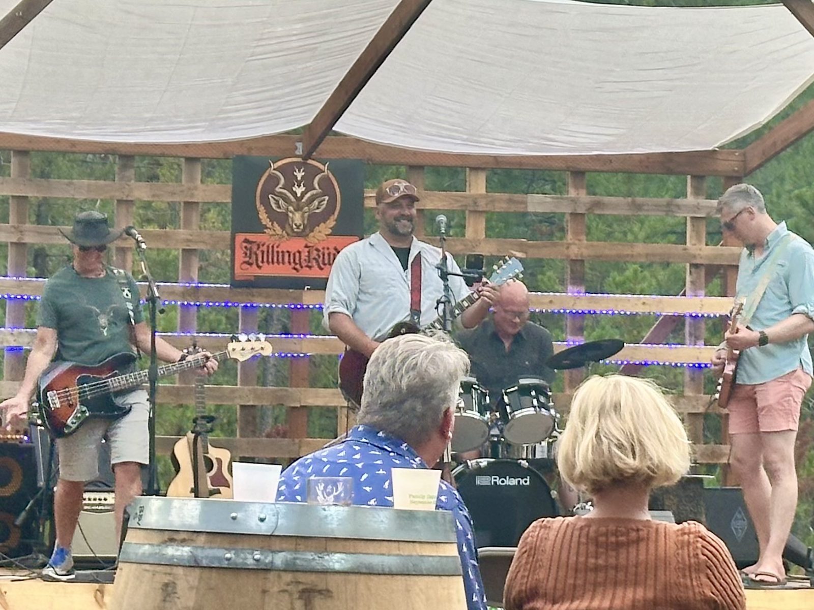 Killing Kudu playing under a canopy at Abbelone Vineyard, the band banner hanging behind the drums